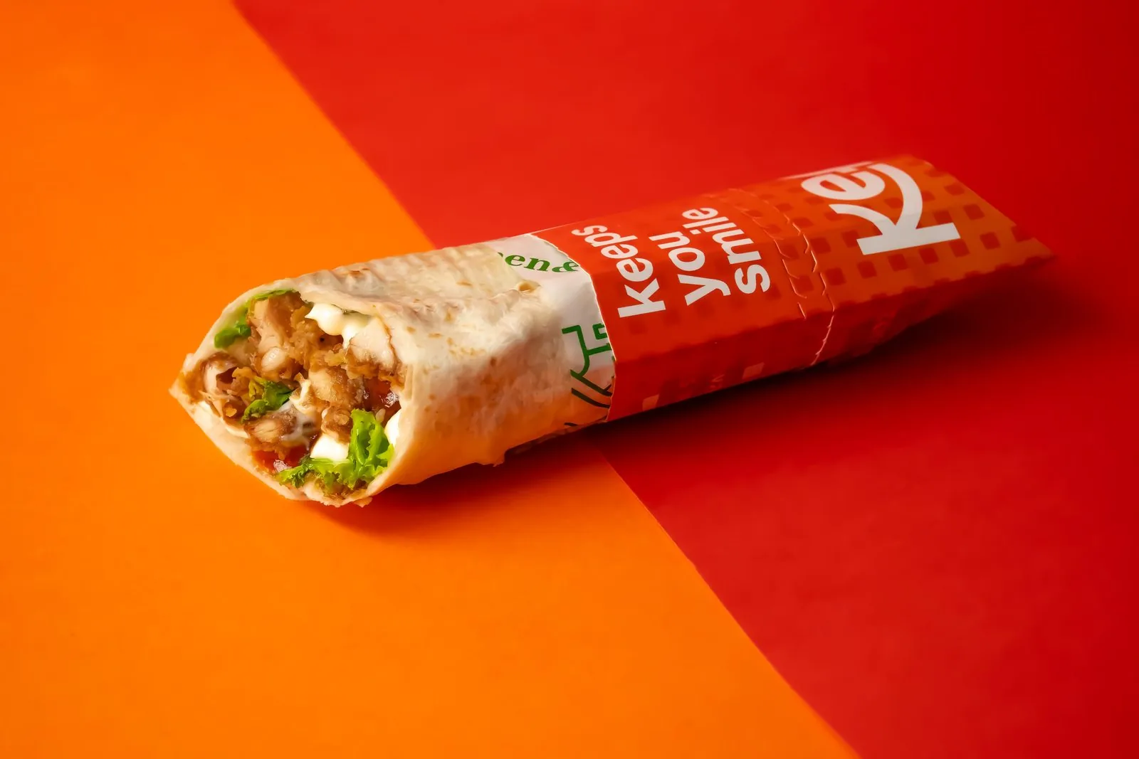 A KEF crispy chicken wrap on the brand's red and orange studio backdrop